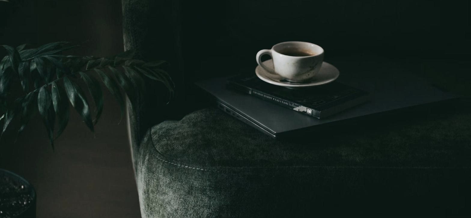 Kaffeetasse auf Laptop auf grünem Samtsessel